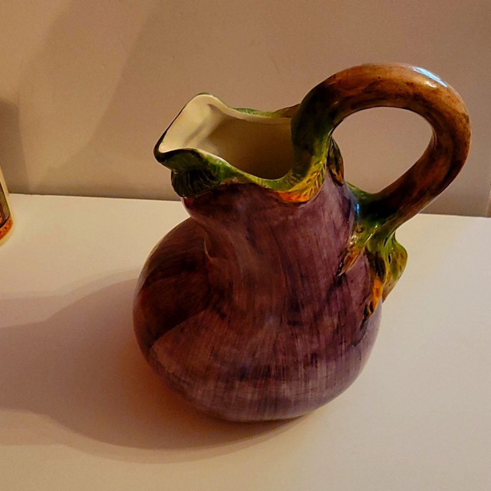 A pitcher made to resemble a Majolica egg.  Color is purple, made in Italy.